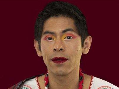 Image of person wearing bright make-up against a maroon background wearing white and floral garments