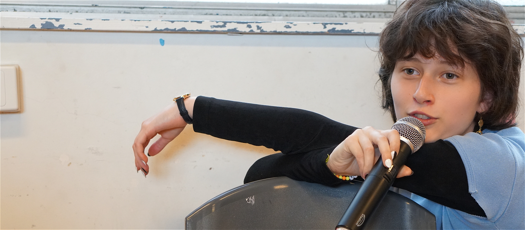 Happy looking young person talking into a microphone, looking relaxed