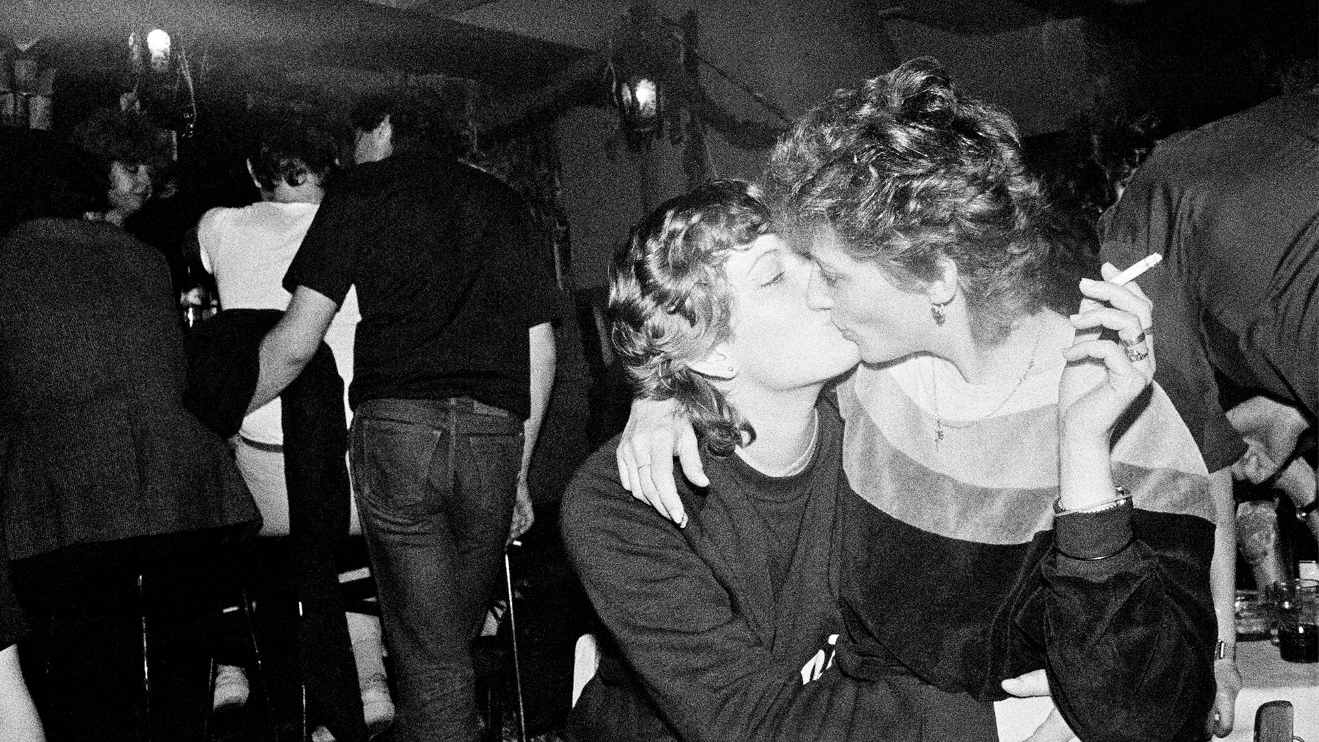 Black and white photo of two people kissing in a club environment