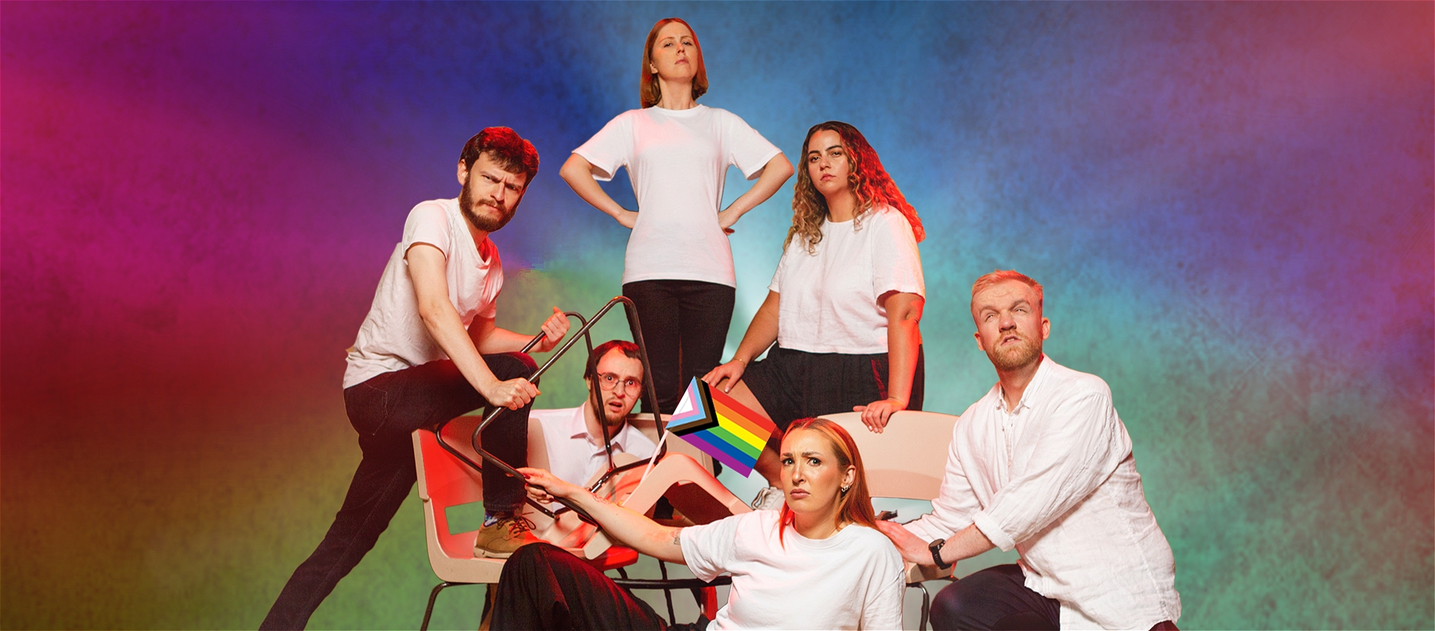 Six cast members of Les Improvisé striking a pose with one holding a gay flag