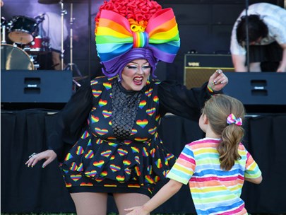 A child interacting with an adult wearing a large rainbow headdress