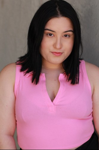 Headshot of Sarah. They have black, silky shoulder length hair, dark eyes and pale skin. They are wearing a hot pink blouse.