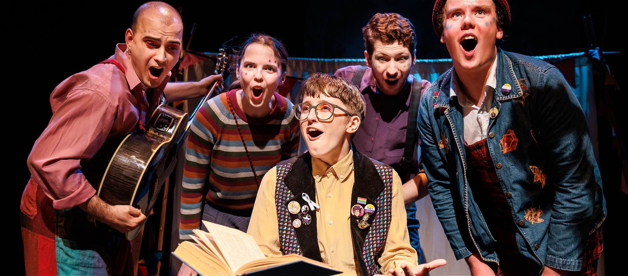 Four people gather round a person reading excitedly from a book