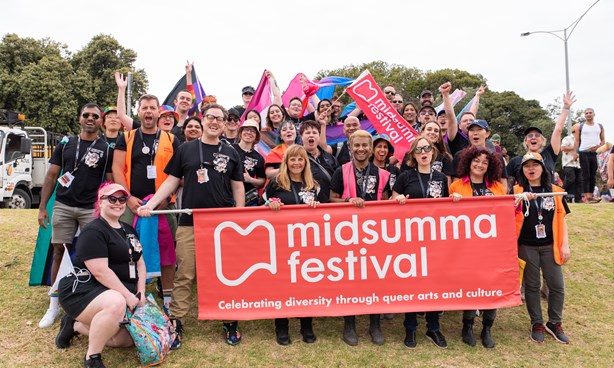 Midsumma staff and volunteers standing behind the Midsumma banner at Pride March 2023