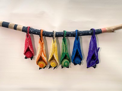 Coloured knitted bat-like figures attached to a wooden stick