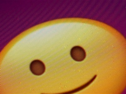 A smiley face icon and computer mouse cursor, pixelated on a screen with a purple and black background
