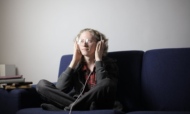 Person sitting on couch - listening to audio through their headphones