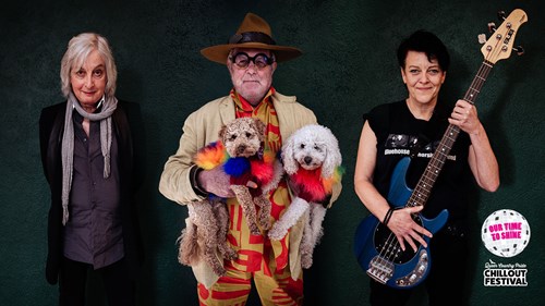 Three people against a black background: one holding a guitar, one holding two dogs