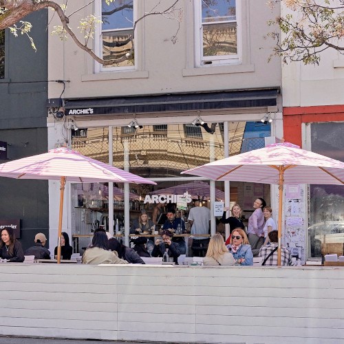 Front of the Archies cafe showing people sitting at tables under umbrellas